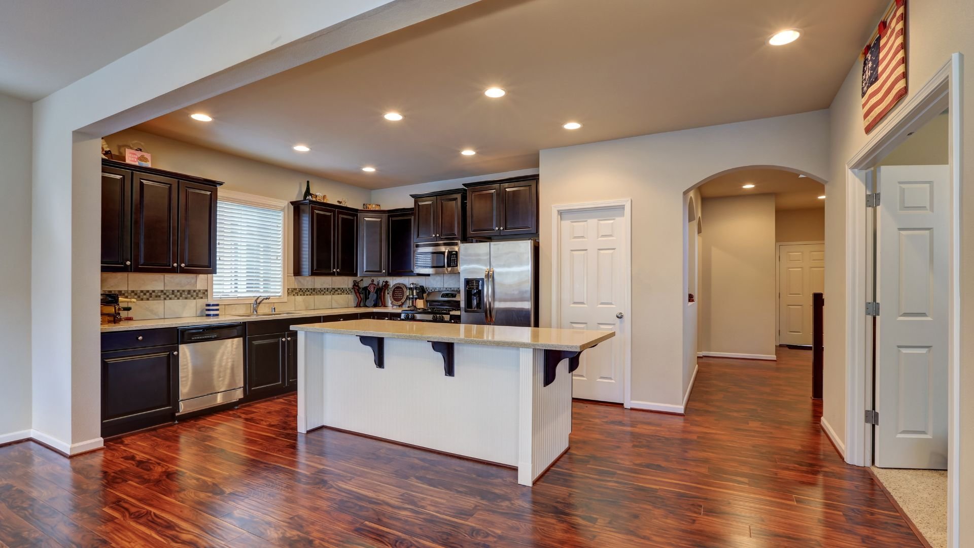 Modern kitchen with dark cabinets, white island, and hardwood floors