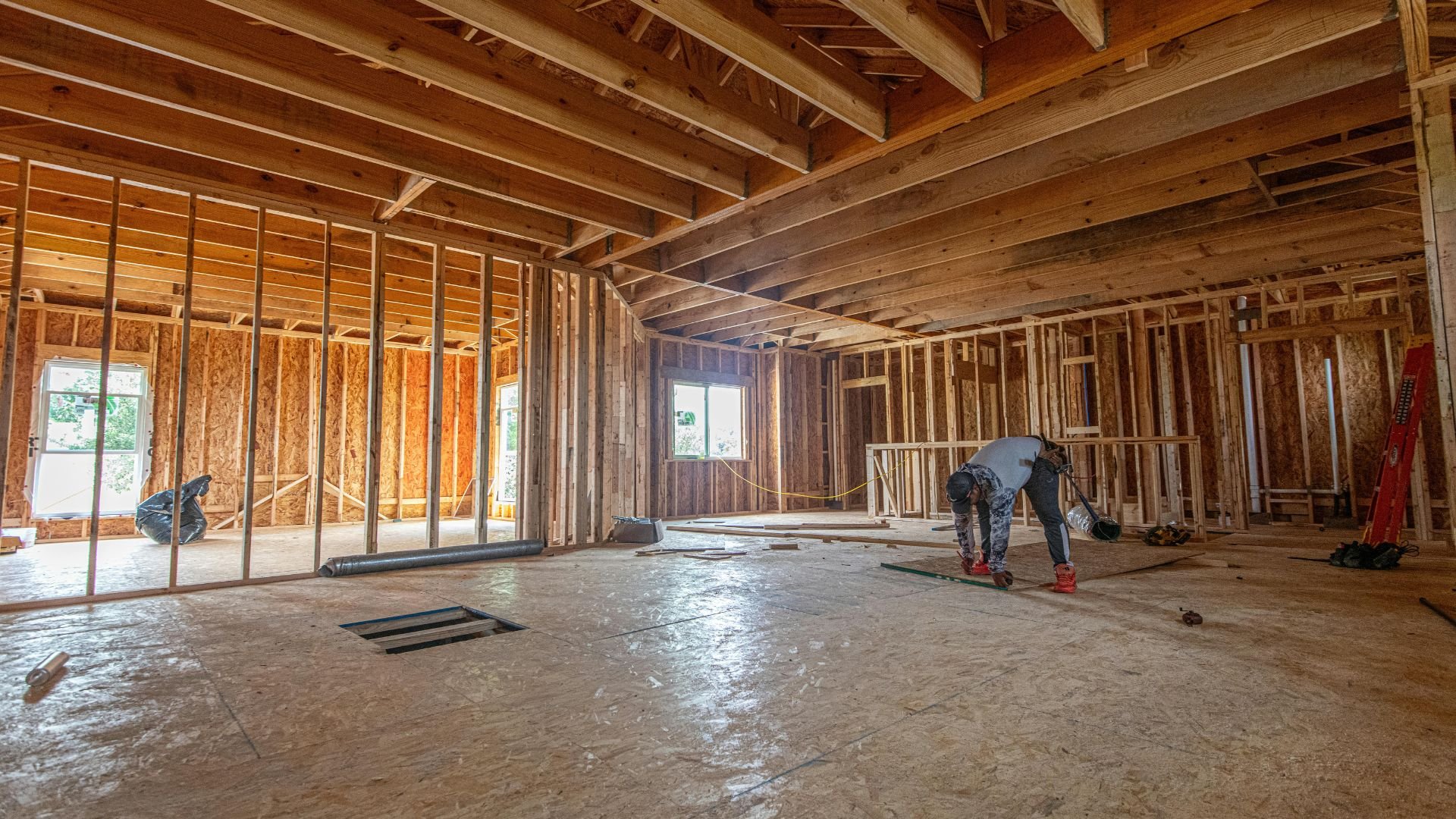 Wooden house interior under construction with exposed framing and workers