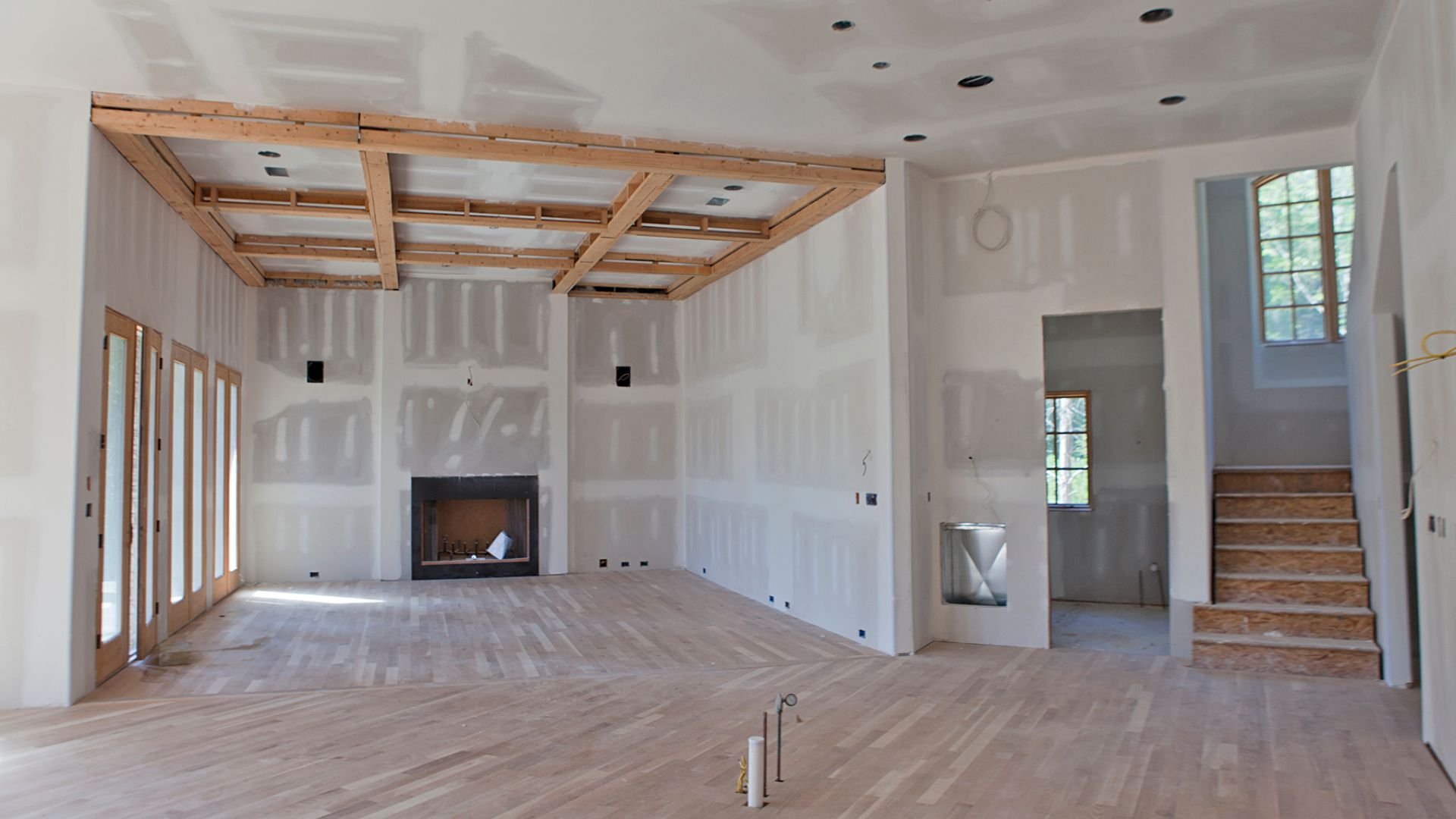 Interior room under construction with exposed wood beams and fireplace