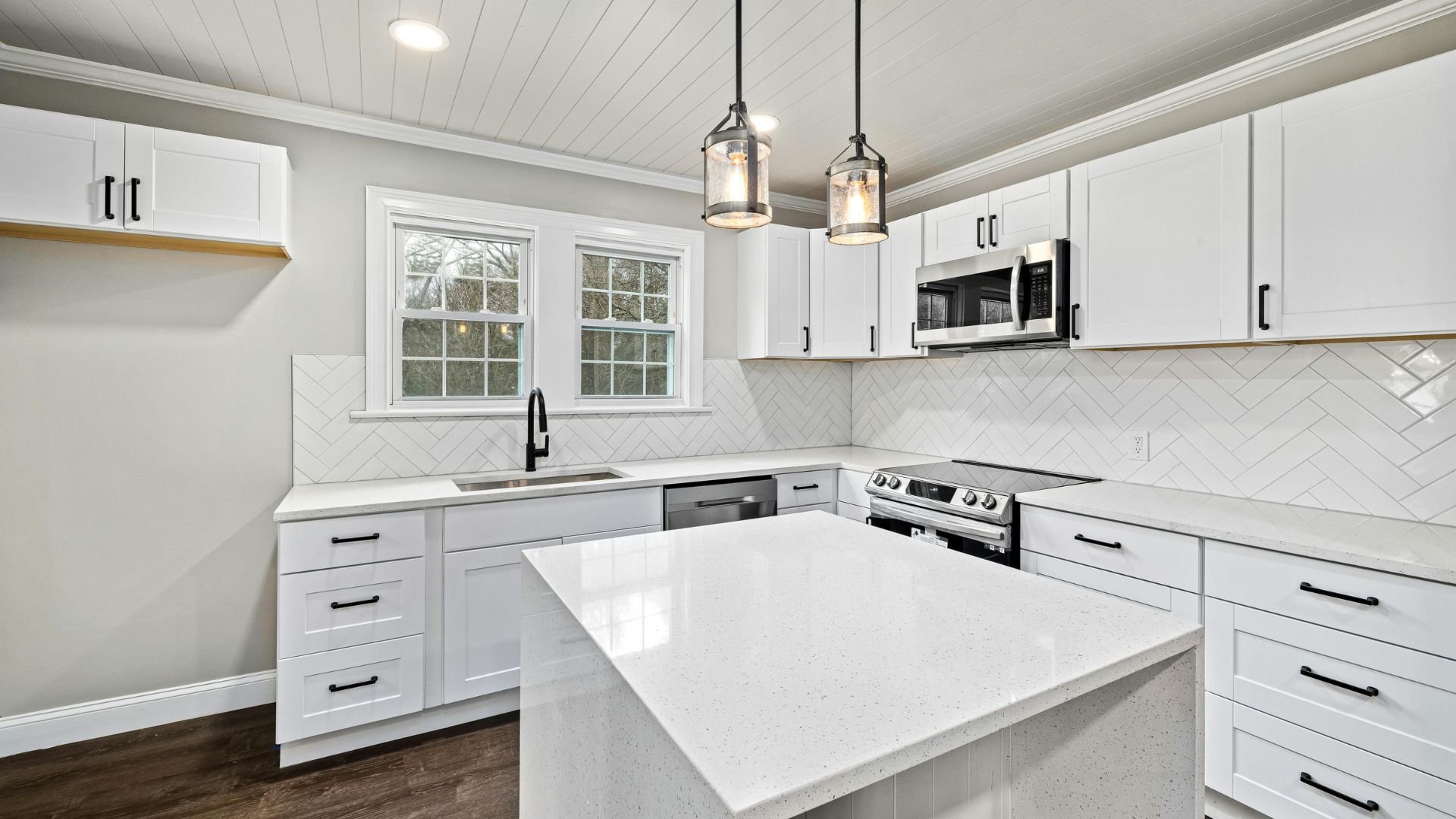 Modern white kitchen with herringbone backsplash and pendant lights