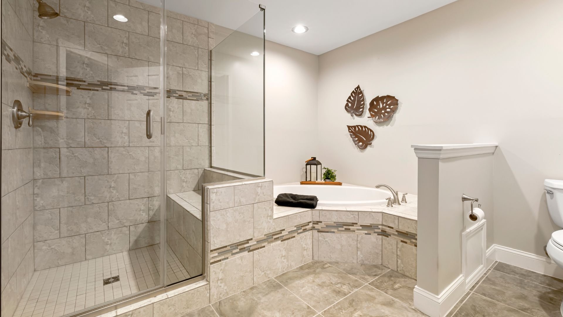 Modern bathroom with glass shower, bathtub, and leaf wall decor