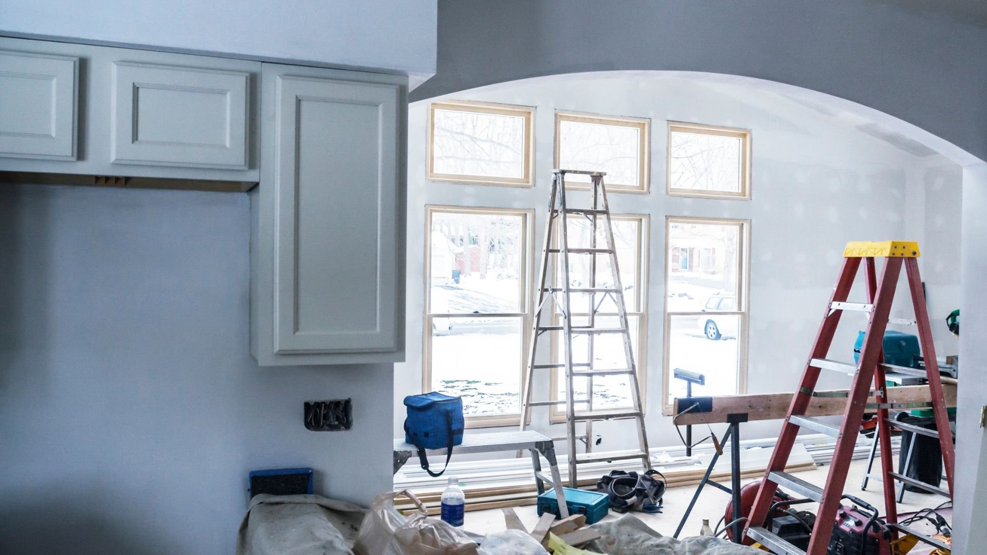 Home renovation in progress with ladders, tools, and construction materials