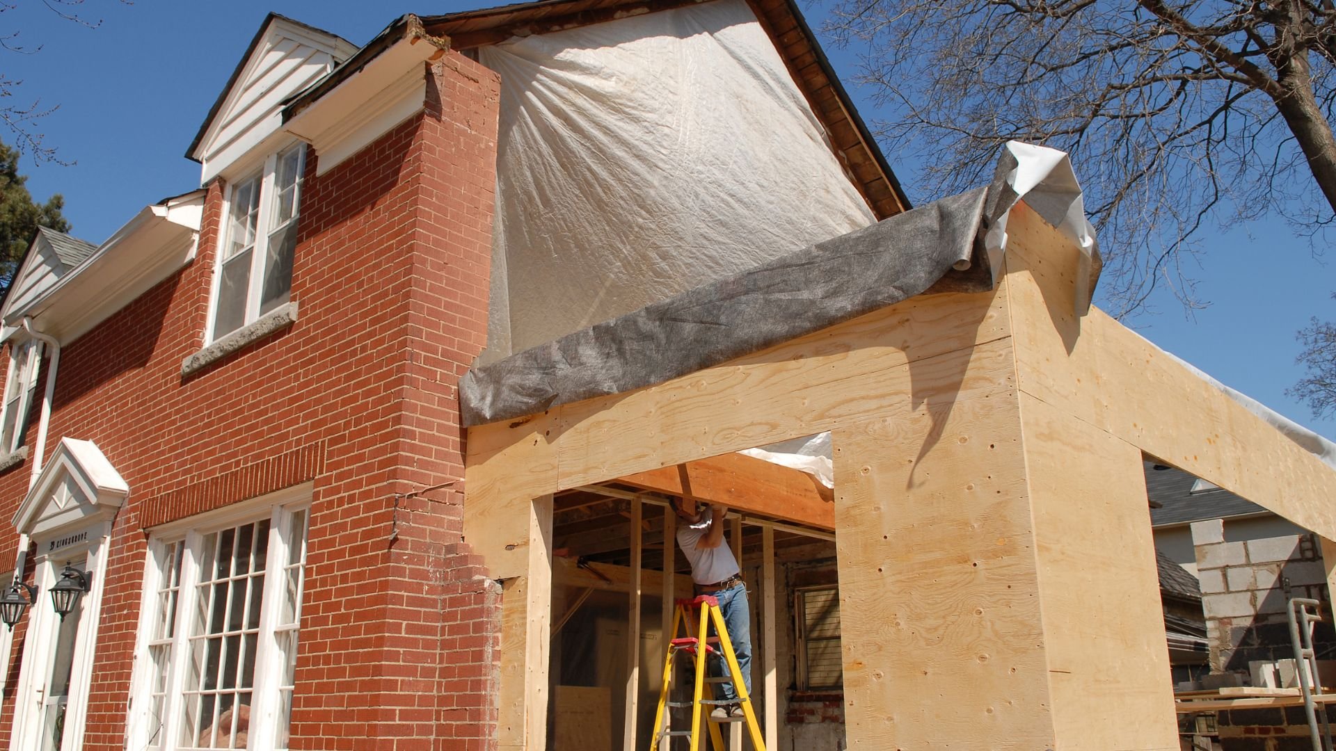 Home renovation with brick house and wooden addition under construction