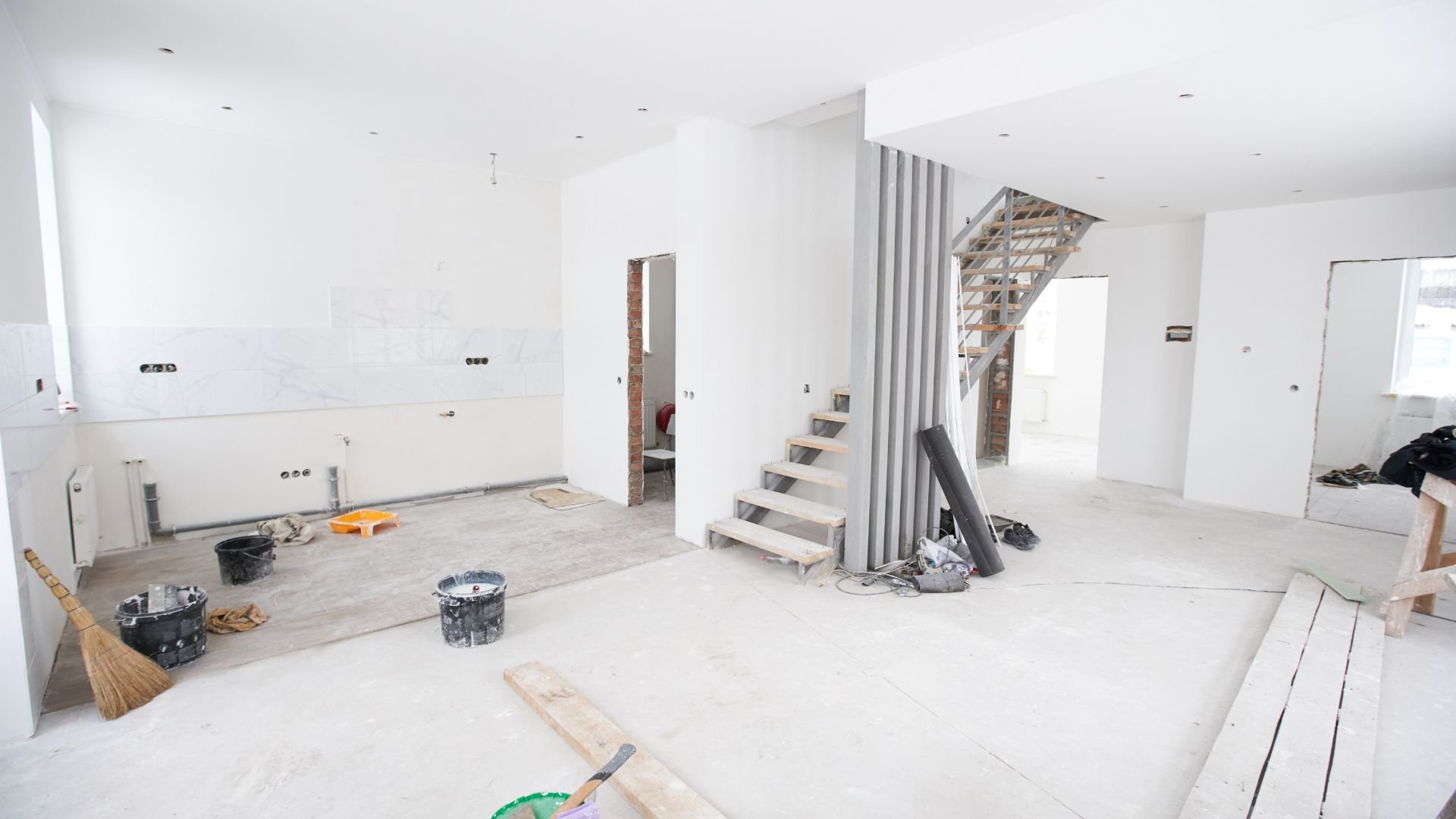 Interior home renovation in progress with construction materials and unfinished stairs