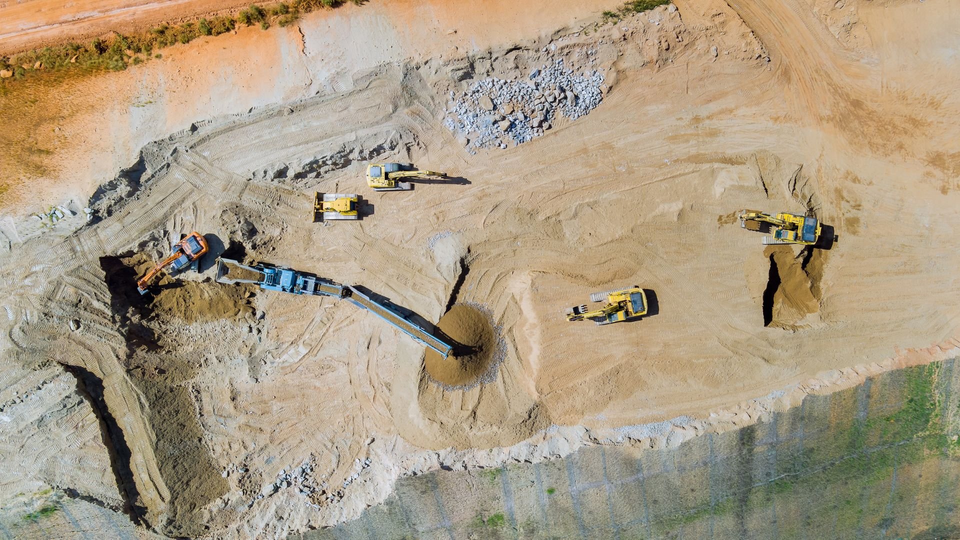 Aerial view of construction site with yellow excavators and machinery